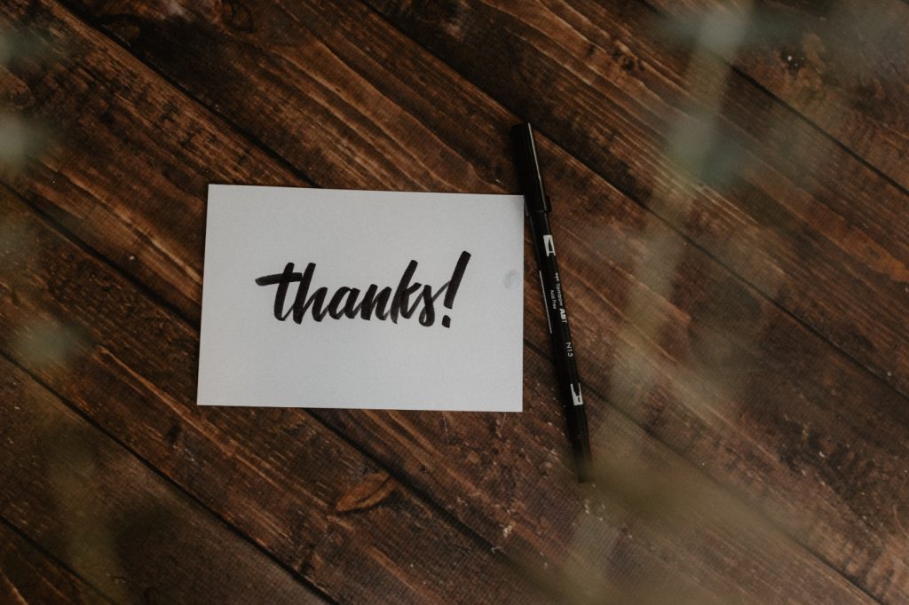 White paper on a desk with "thanks!" written on it.