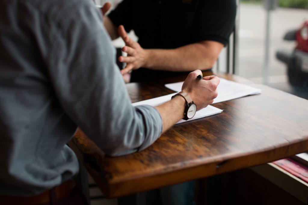 Two people in an engaging conversation sitting at a wooden table.