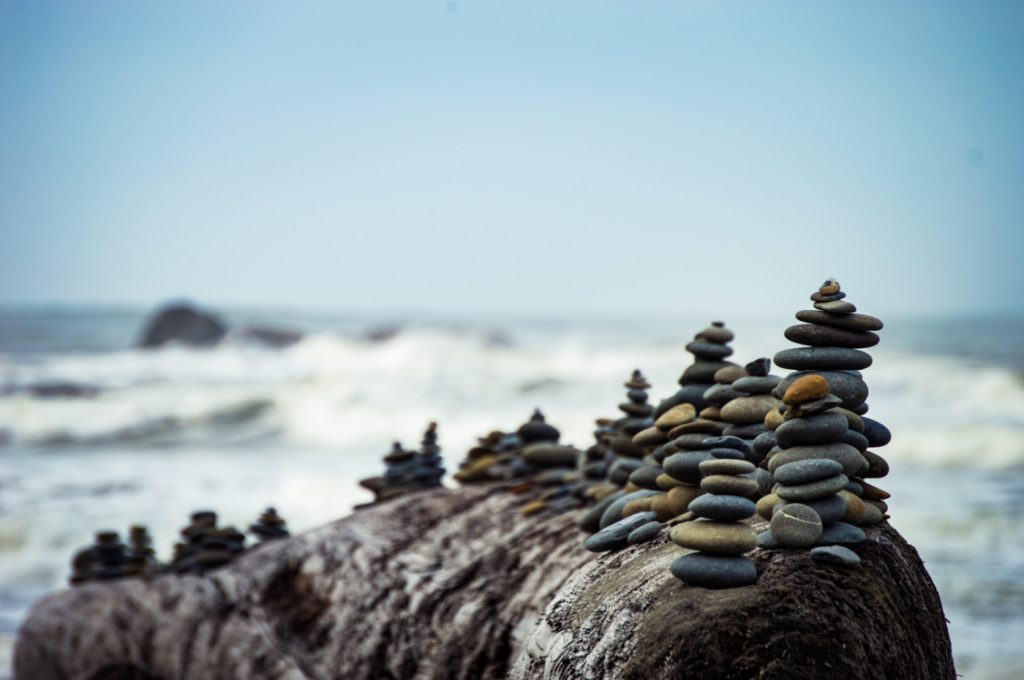 Several intricate pebble piles on a big rock by the sea.