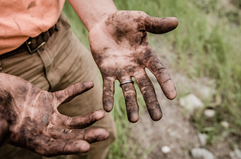 Hands of a man, covered with mud.