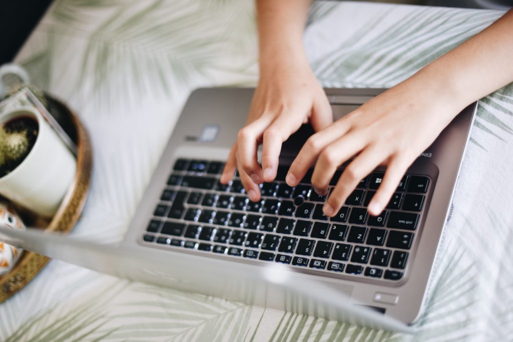 A person typing on a laptop keyboard.