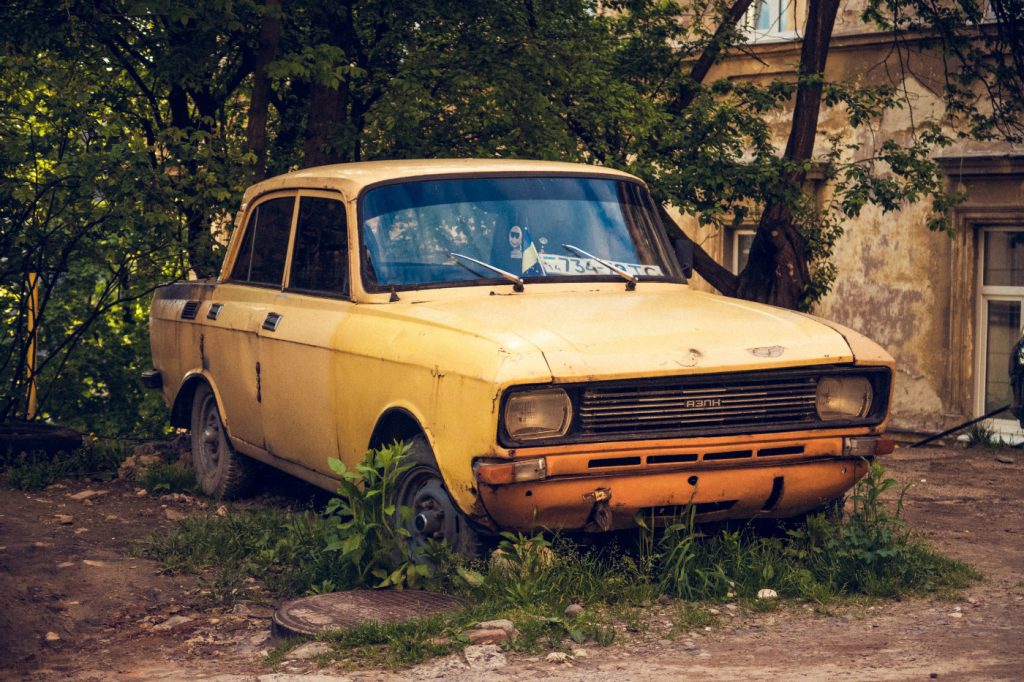 A rusty, old, yellow car in the tall grass.