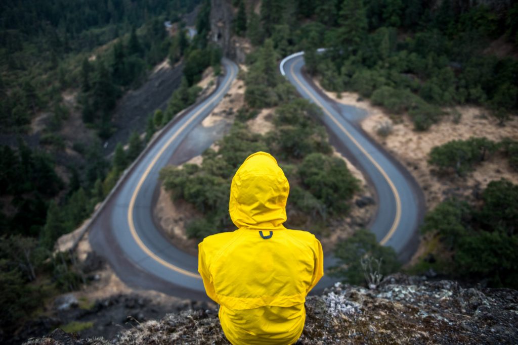 A person on top of a hill sitting over a winding road.