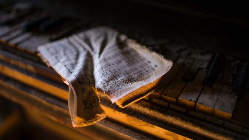 Torn music sheet on decaying piano keys.