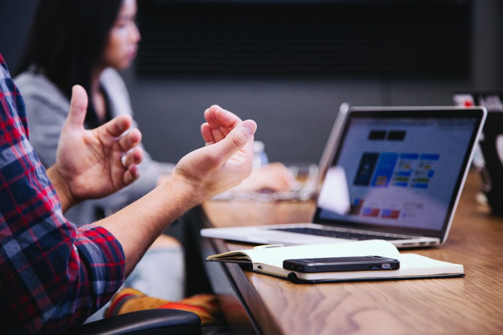 A person gesticulating with hands in front of a laptop.