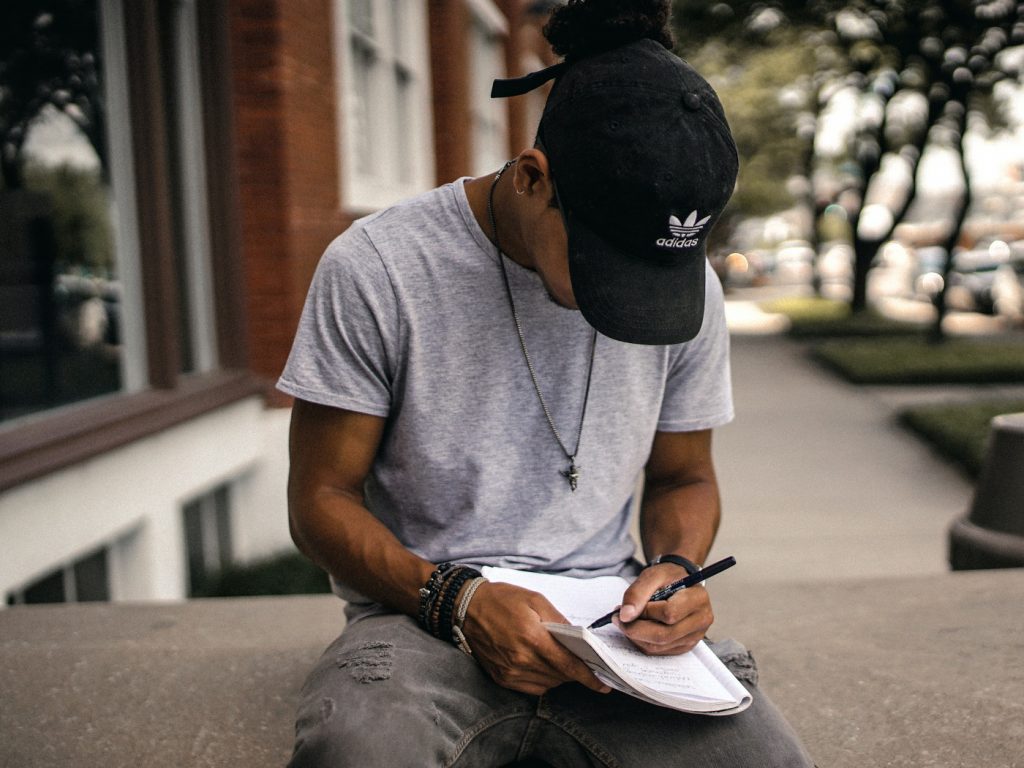 A person sitting on a bench writing in a notebook.