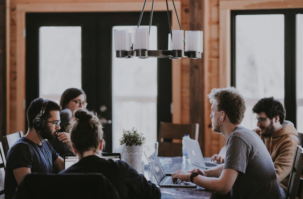 A group of people sitting at a desk, working.