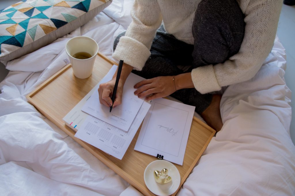 A person holding a pen, reviewing some papers on a wooden table.