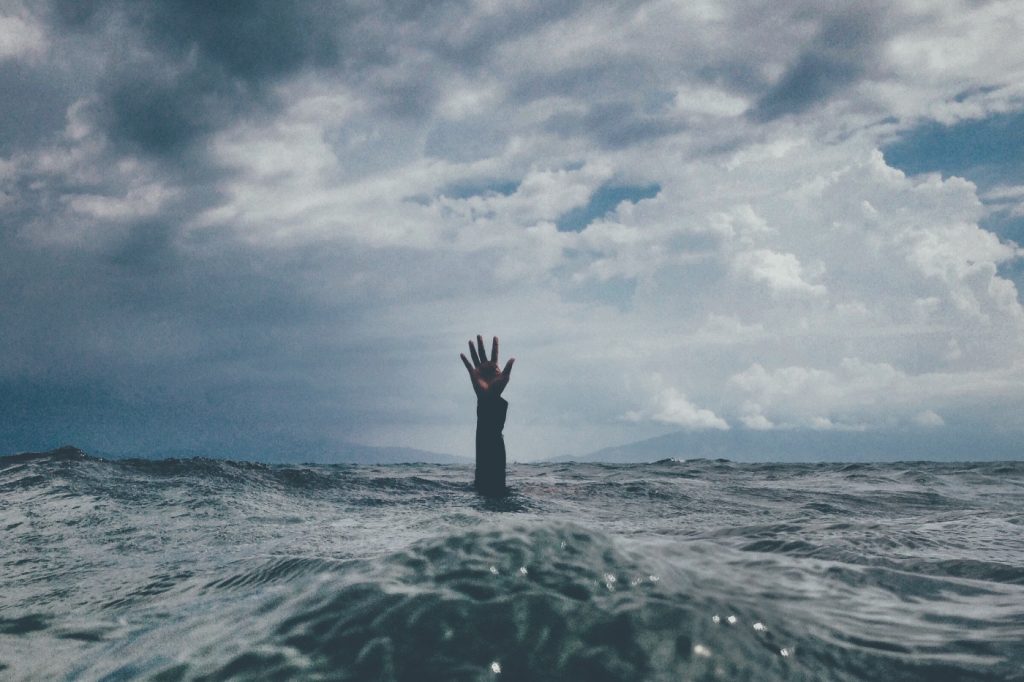 A person's hand reaching out from deep water.