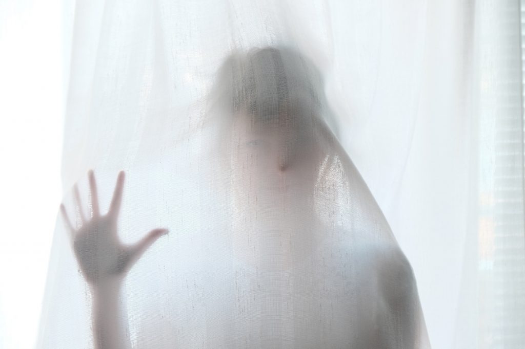 A silhouette of a woman behind a shower curtain.