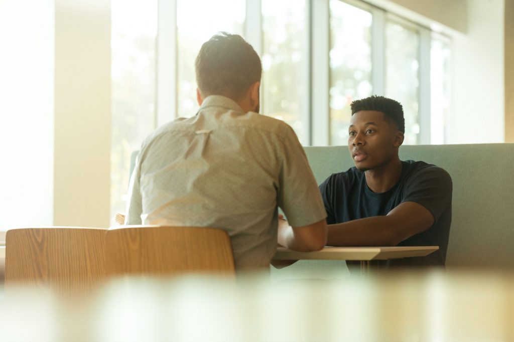 Two men in a discussion at a table.