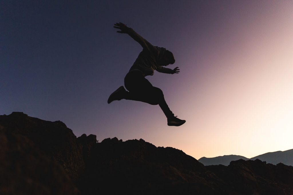 A person jumping above mountains.