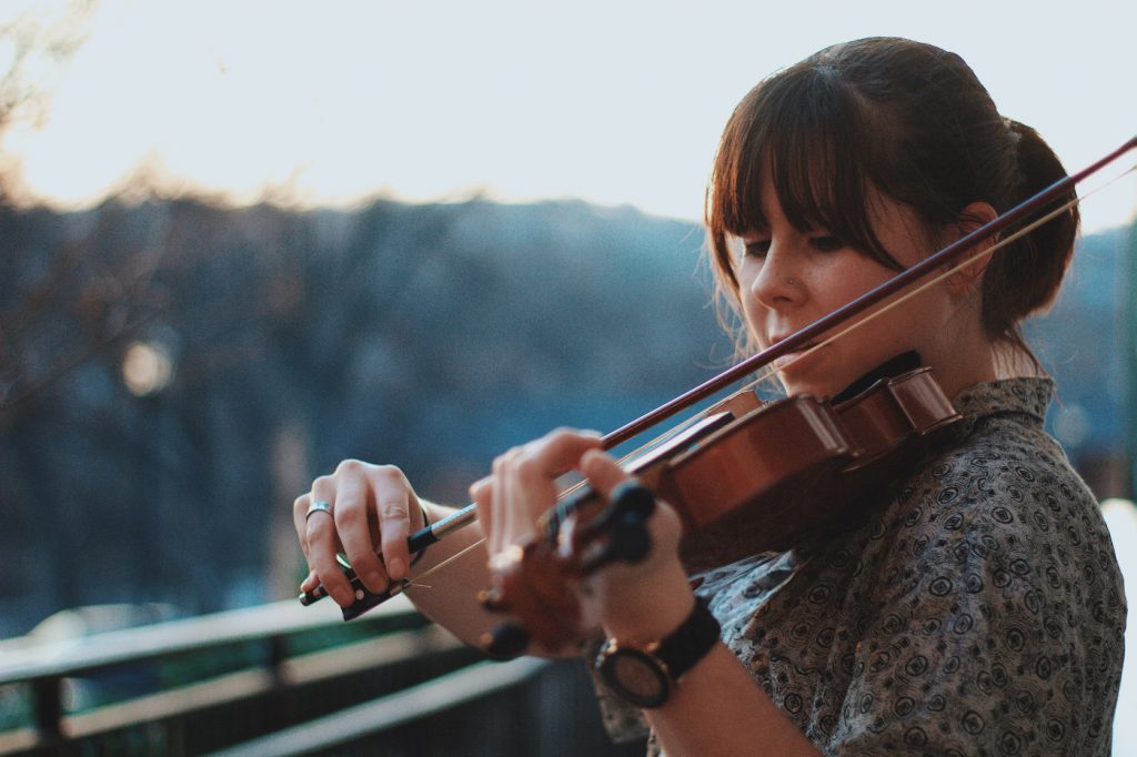A woman practicing violin outdoors.