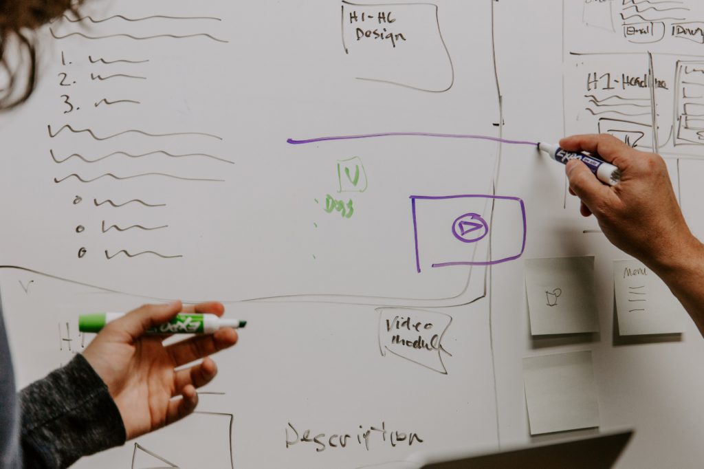 Two people drawing on a whiteboard.