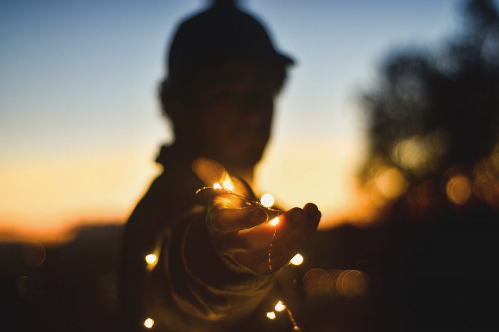 A person reaching out holding string lights.