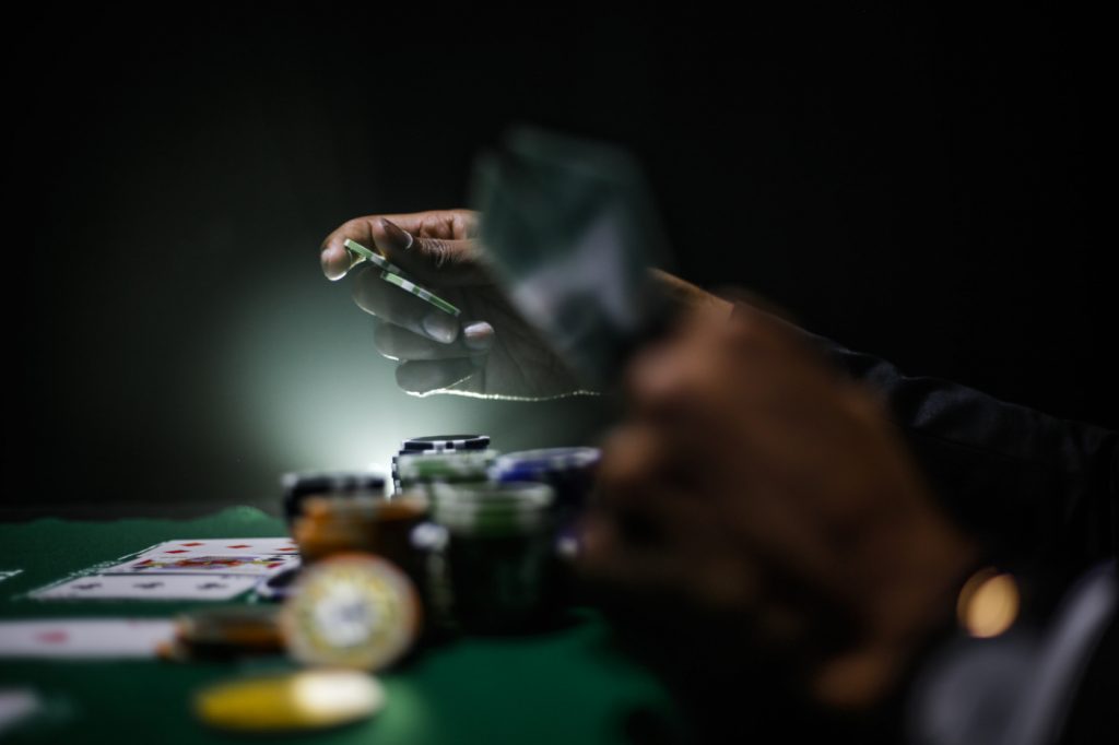 A person holding chips and cards on a poker table.