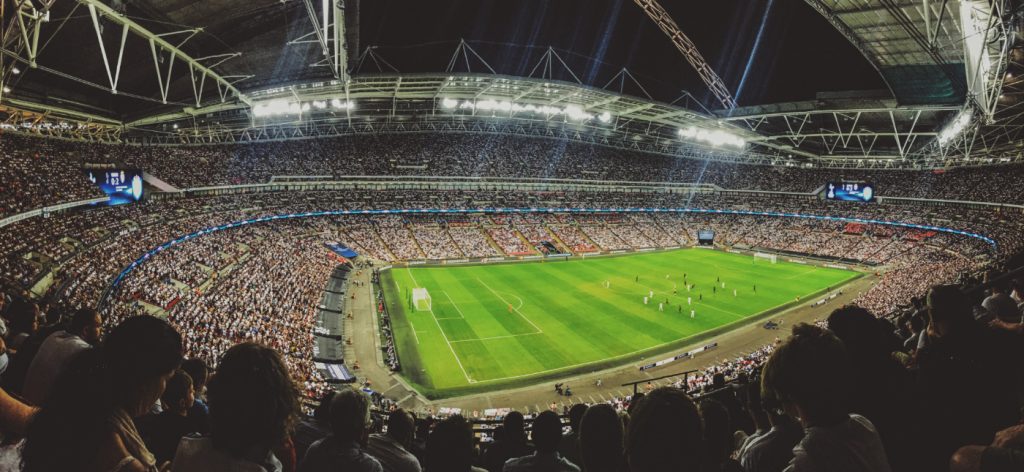 A massive crowd watching a football game in a stadium.