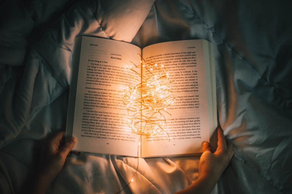 A person holding string lights on an opened book.