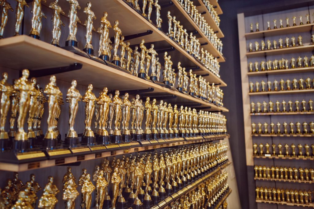 Numerous Oscar awards on shelves.