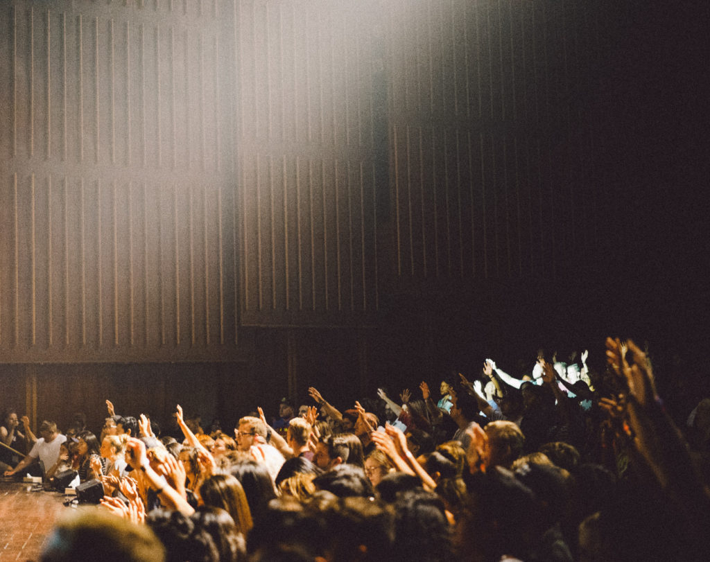 A bunch of people in a crowd raising their hands.