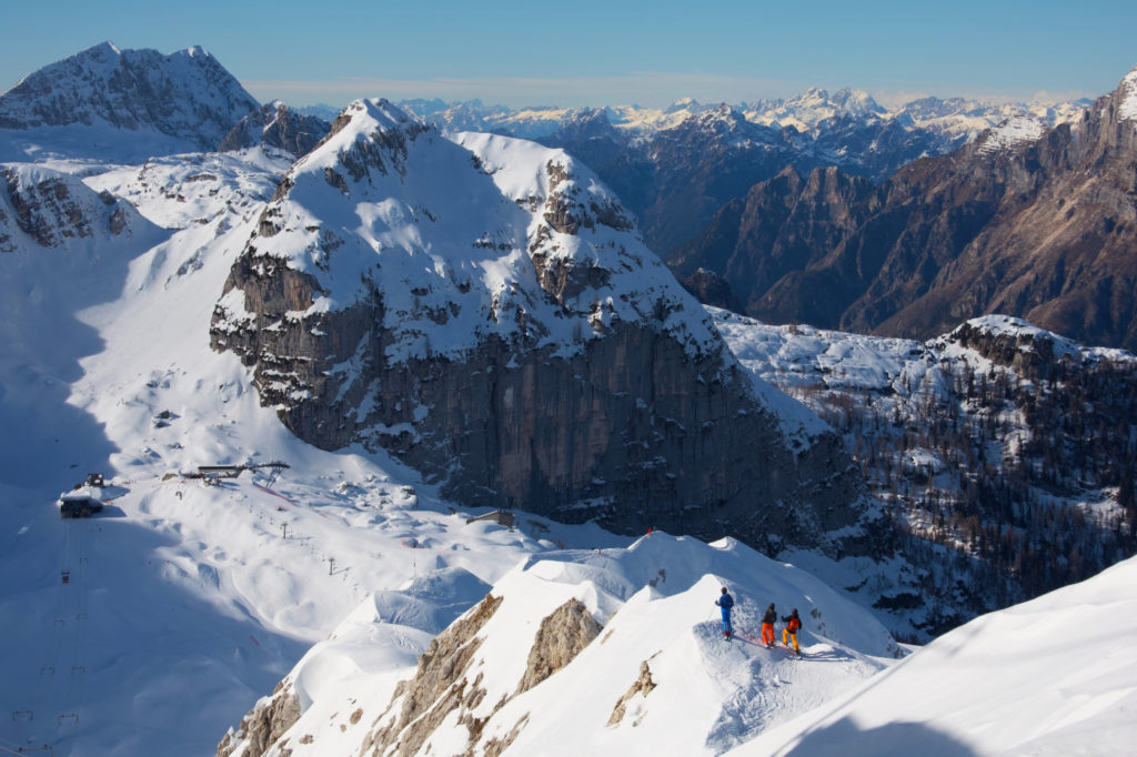 Three people standing on top of a snow-covered mountain.