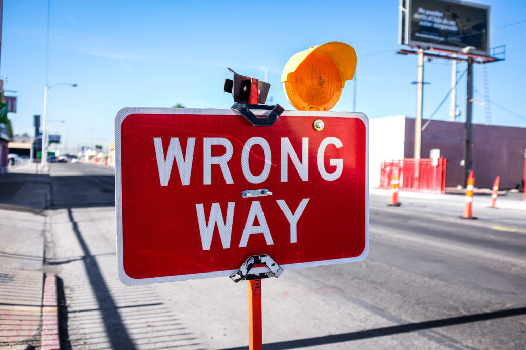 Red "Wrong Way" sign on the road.