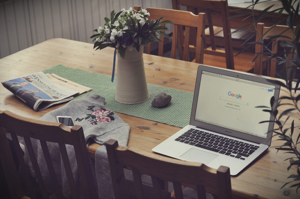 A laptop on a desk with a web page of a search engine opened.