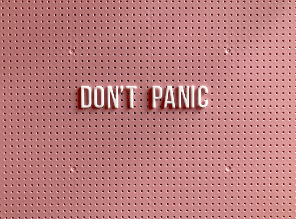 A sign on a wall that reads “don’t panic.”