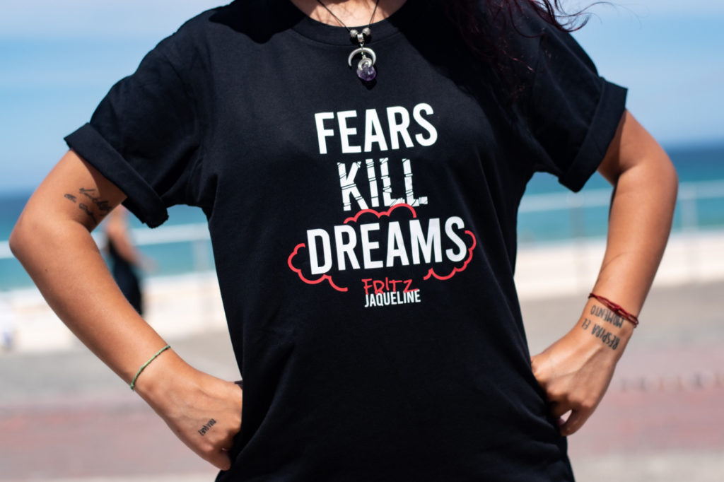 A person wearing a shirt with the inscription "fears kill dreams."