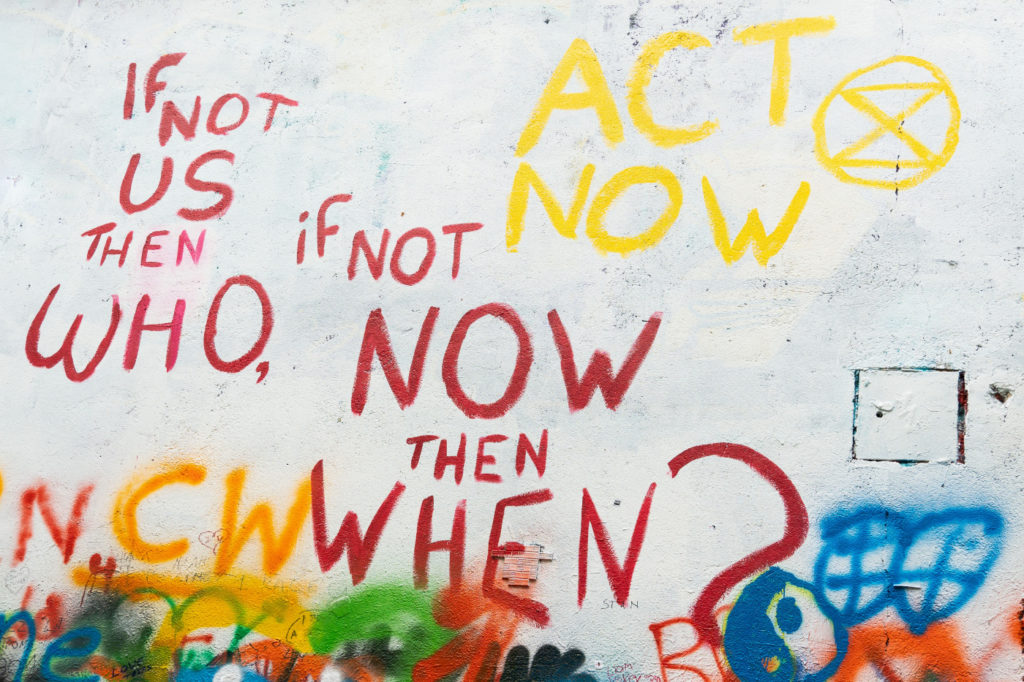 A graffiti wall with the statement: "If not us then who, if not now then when? Act now."