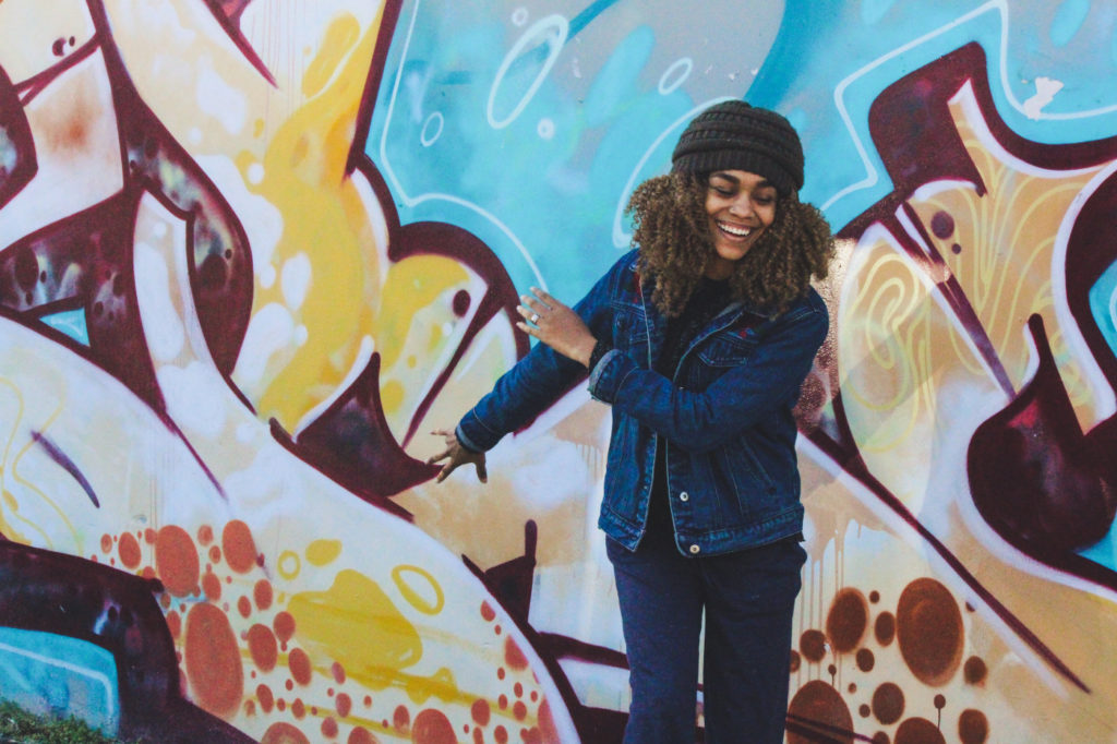 A woman smiling in front of graffiti.