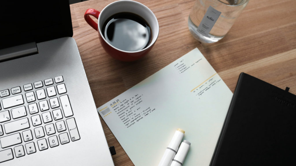 A paper with a date on a desk next to a laptop.