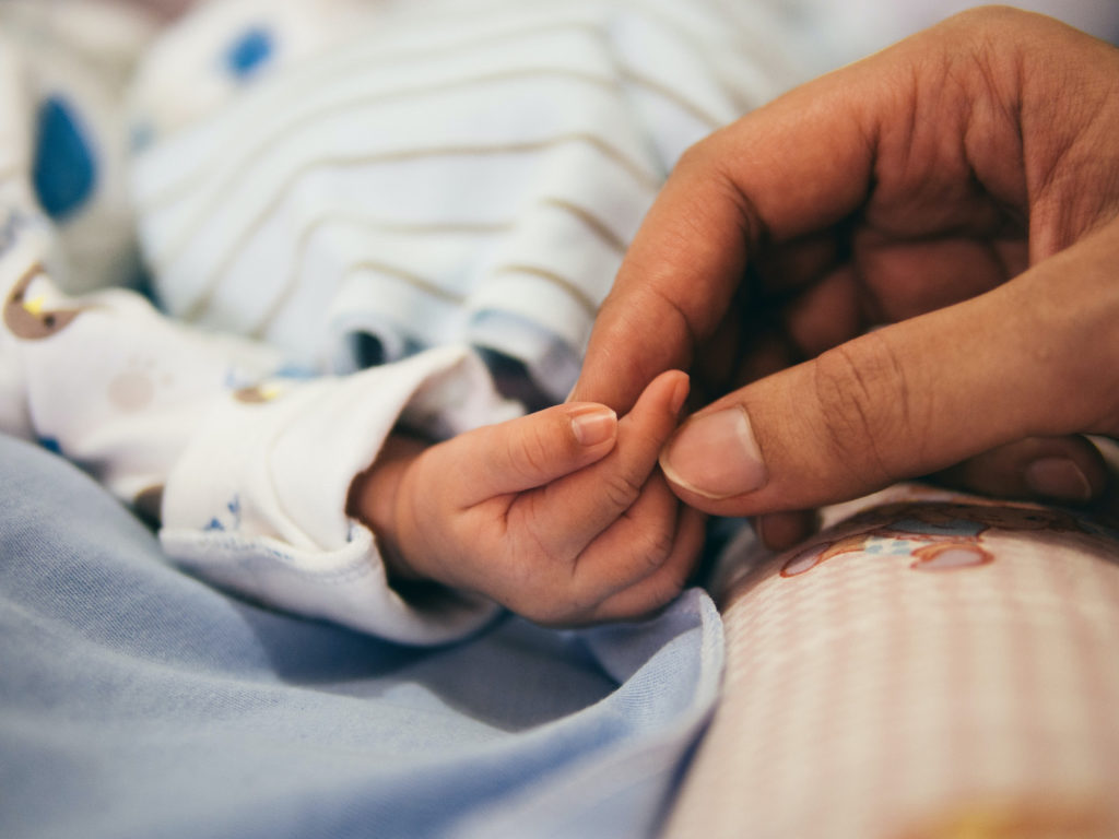 A person holding a newborn's hand.