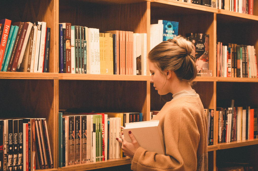 A person looking for a book in a library.