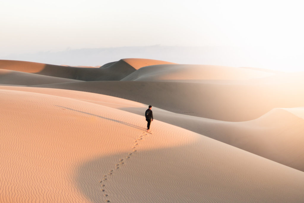 A person walking on a dune in a desert.