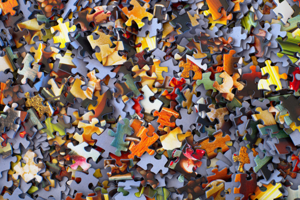 A pile of jigsaw puzzle pieces on a desk.