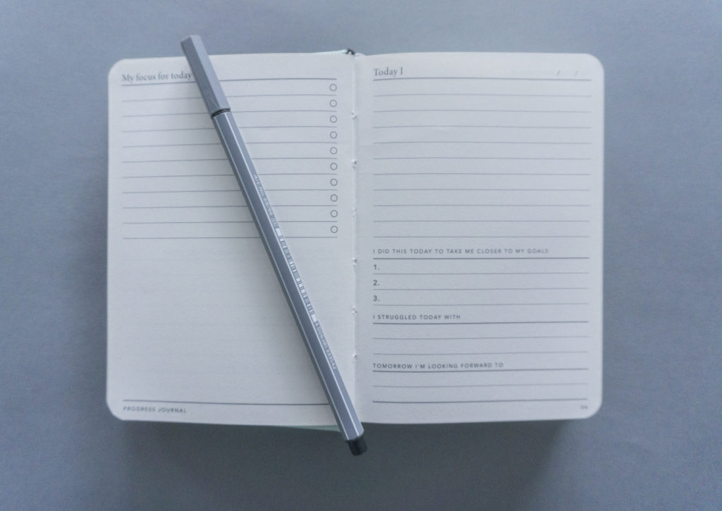 An open and empty goal progress journal on a desk.