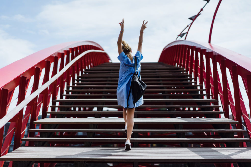 A person cheerfully walking over a bridge.