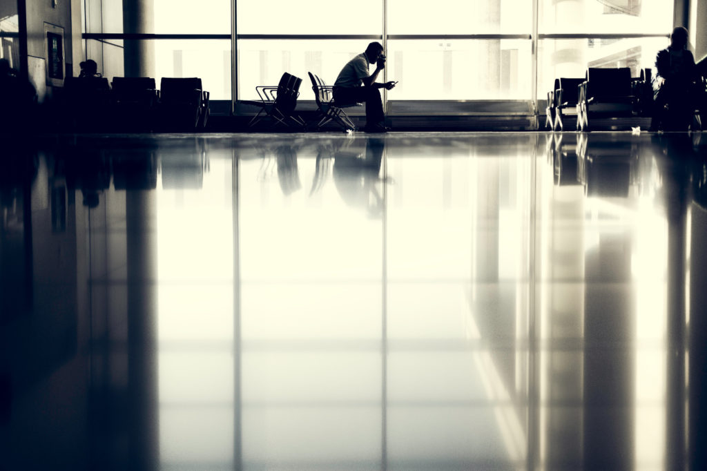 A person waiting at an airport with a mobile phone in their hand.