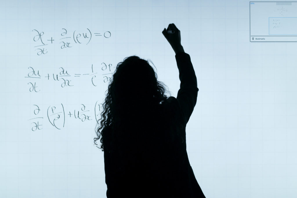 An engineer writing equations on a whiteboard.