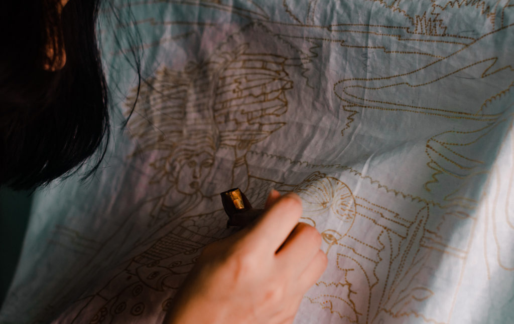 A person drawing on cloth using a batik technique.