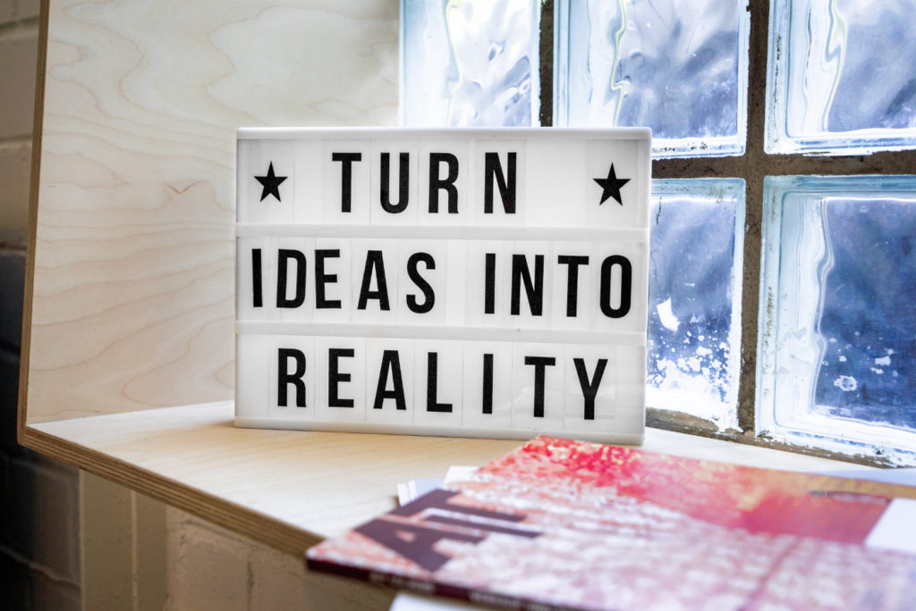 A sign next to a window that reads "turn ideas into reality."