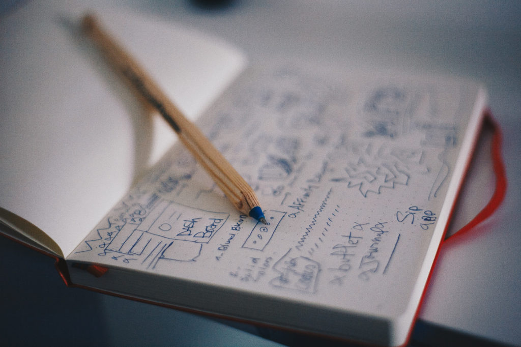 A pen on an open notebook with wireframes on the page.