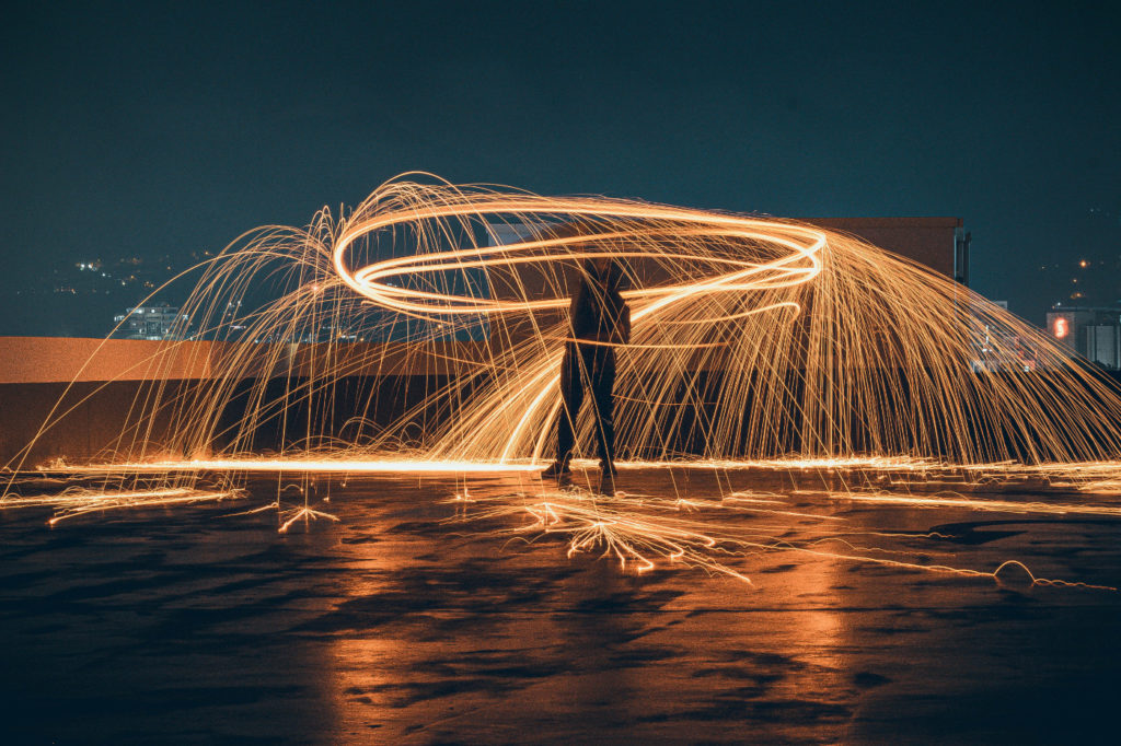 A person celebrating by creating an impressive light painting in the dark.