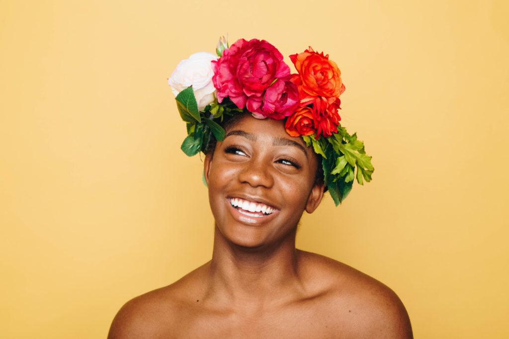 A person with flowers in their hair confidently smiling.