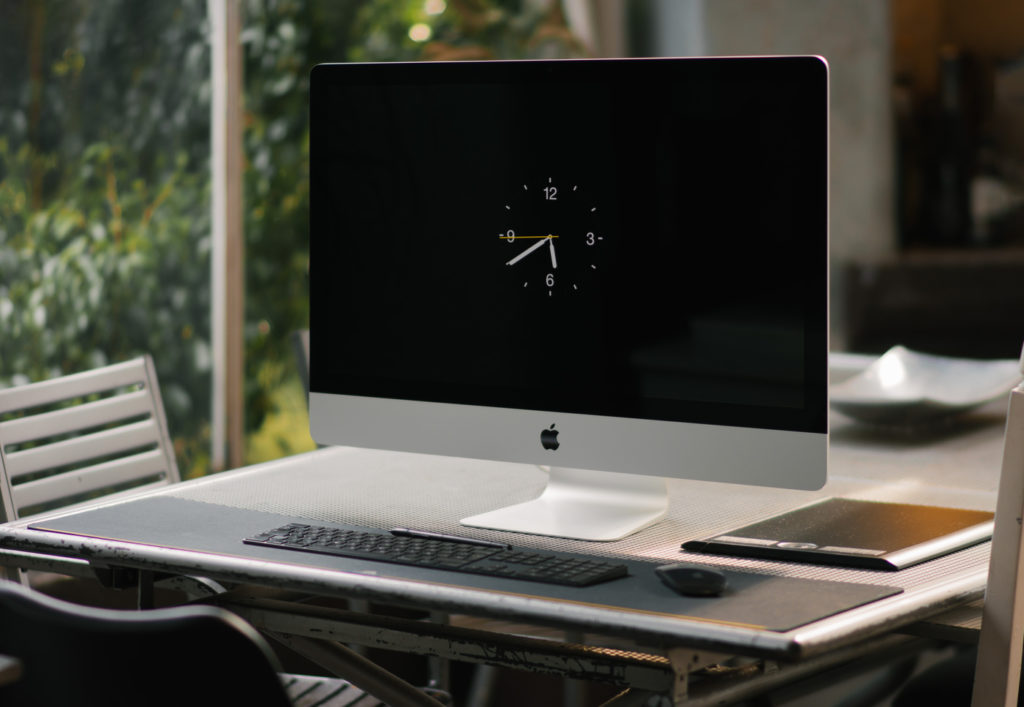 A computer on a desk with a screensaver showing a clock with time 6:40 pm.