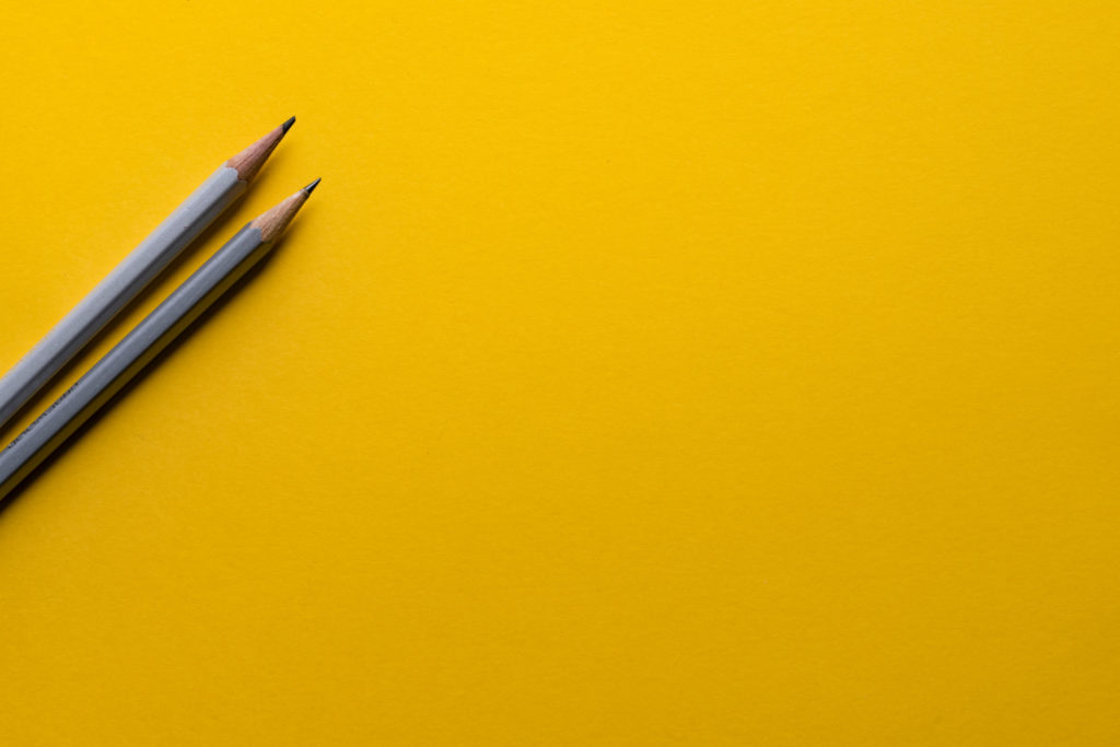 Two pencils on a yellow background.